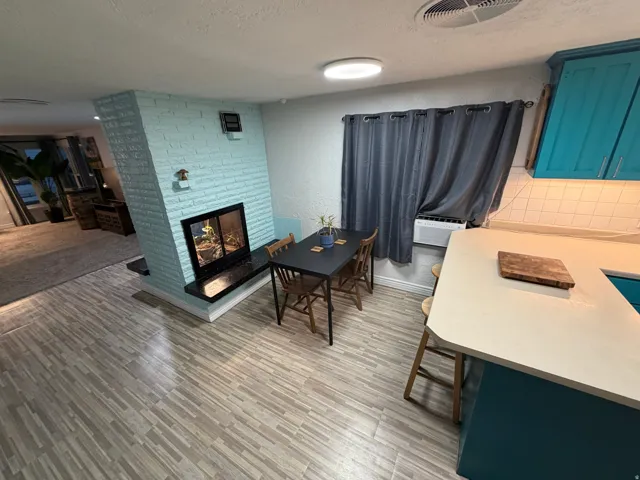 Brick fireplace with a dark hearth, wood-finish flooring, white countertop, and blue cabinetry