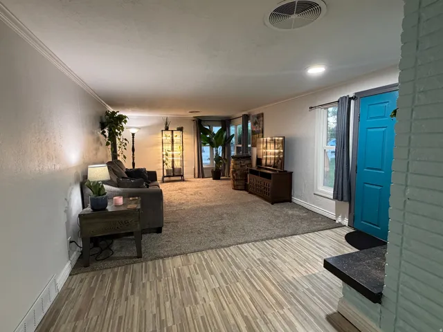 Wood-finish flooring at entry, leading to carpeted living space