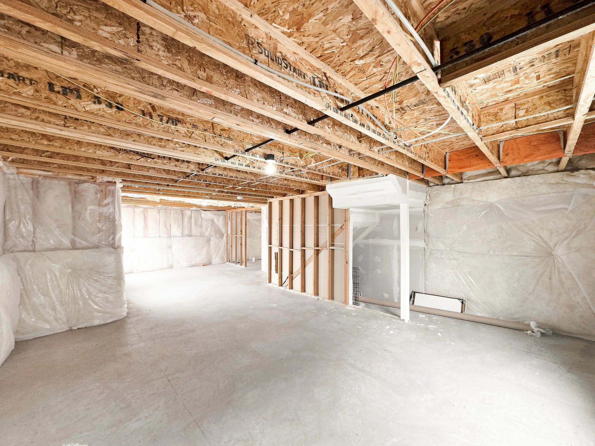 Unfinished basement featuring exposed joists, concrete flooring, framed wall sections, and insulated wall sections