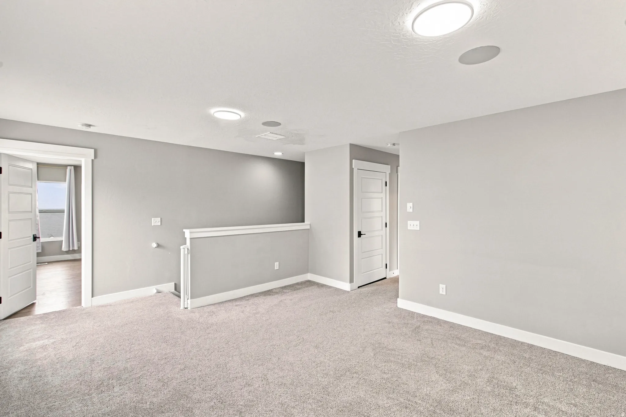 Spacious interior featuring neutral carpeting, light gray wall tones, contemporary panel doors, and recessed ceiling lighting