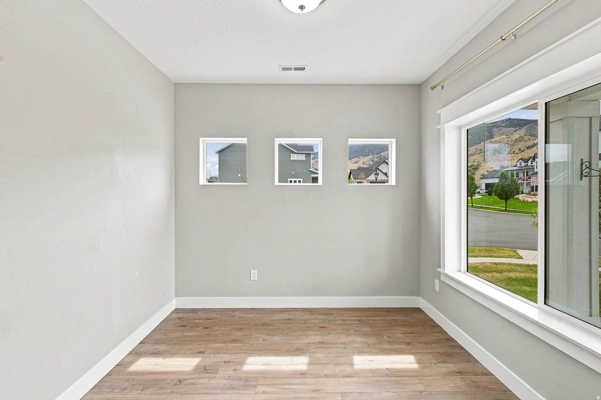 Wood-finish flooring, three square windows, and a large sliding glass door with white trim