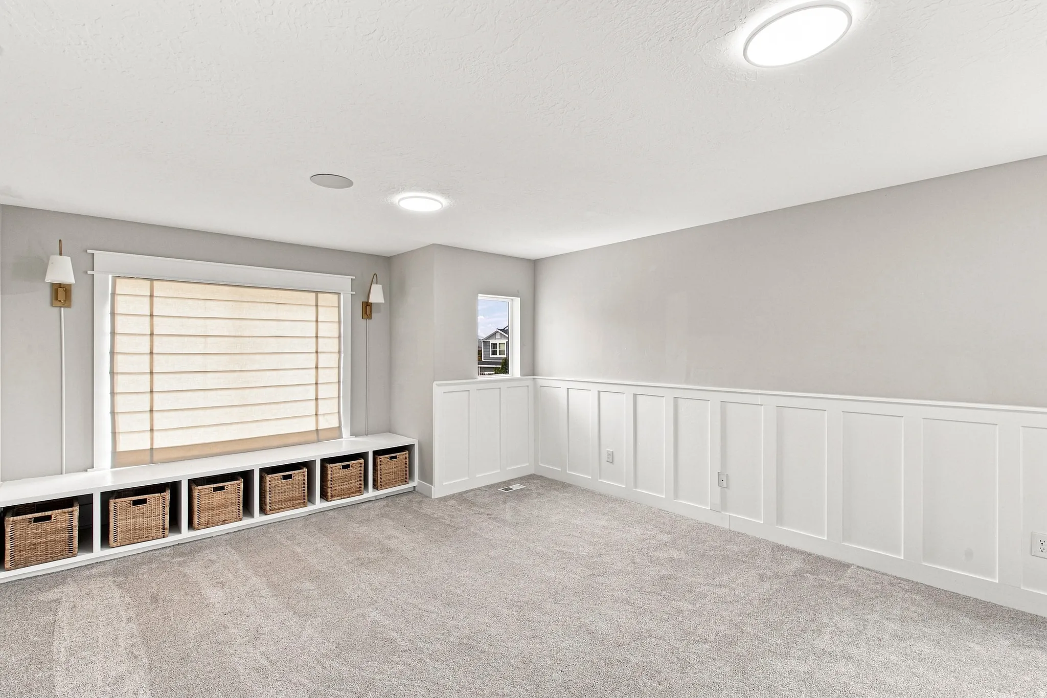 Built-in window bench with integrated storage cubbies, board and batten wall detailing, wall-mounted sconces, and recessed ceiling lighting