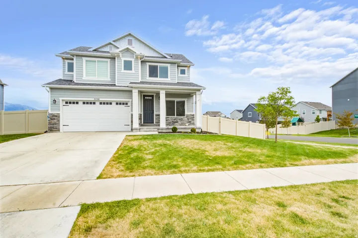 Light gray siding exterior, stone veneer accents, white trim, attached two-car garage, and concrete driveway