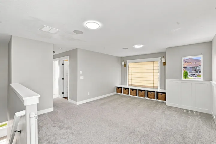 Expansive carpeted area with a built-in window bench featuring integrated storage cubbies