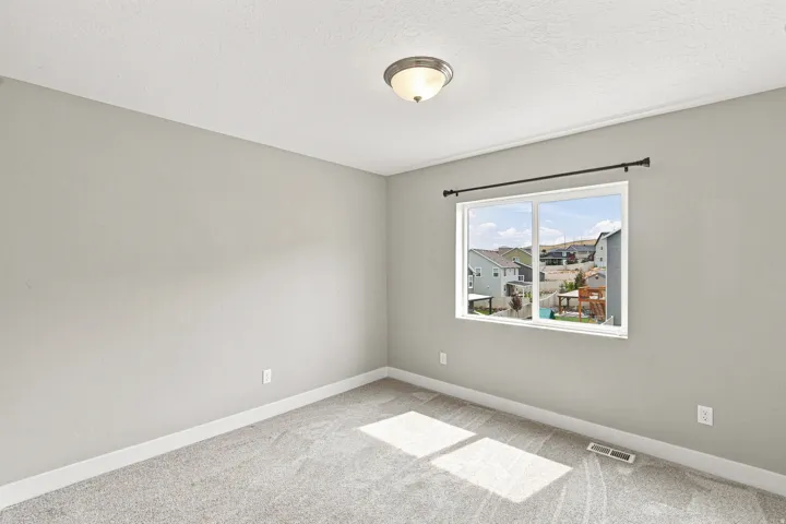 Recessed ceiling light fixture, neutral wall paint, carpeted flooring, and a large window with neighborhood views