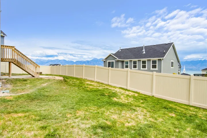 Expansive backyard featuring a partial wood deck and staircase, and a tan privacy fence