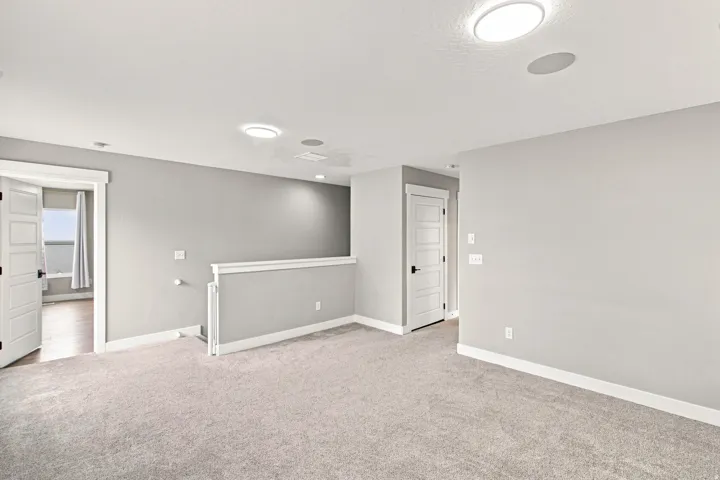 Spacious interior featuring neutral carpeting, light gray wall tones, contemporary panel doors, and recessed ceiling lighting