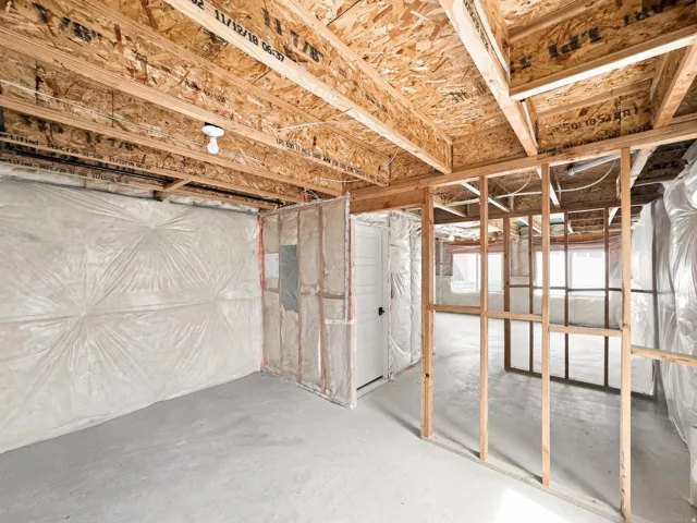 Unfinished basement with concrete flooring, exposed wood framing, and ceiling joists