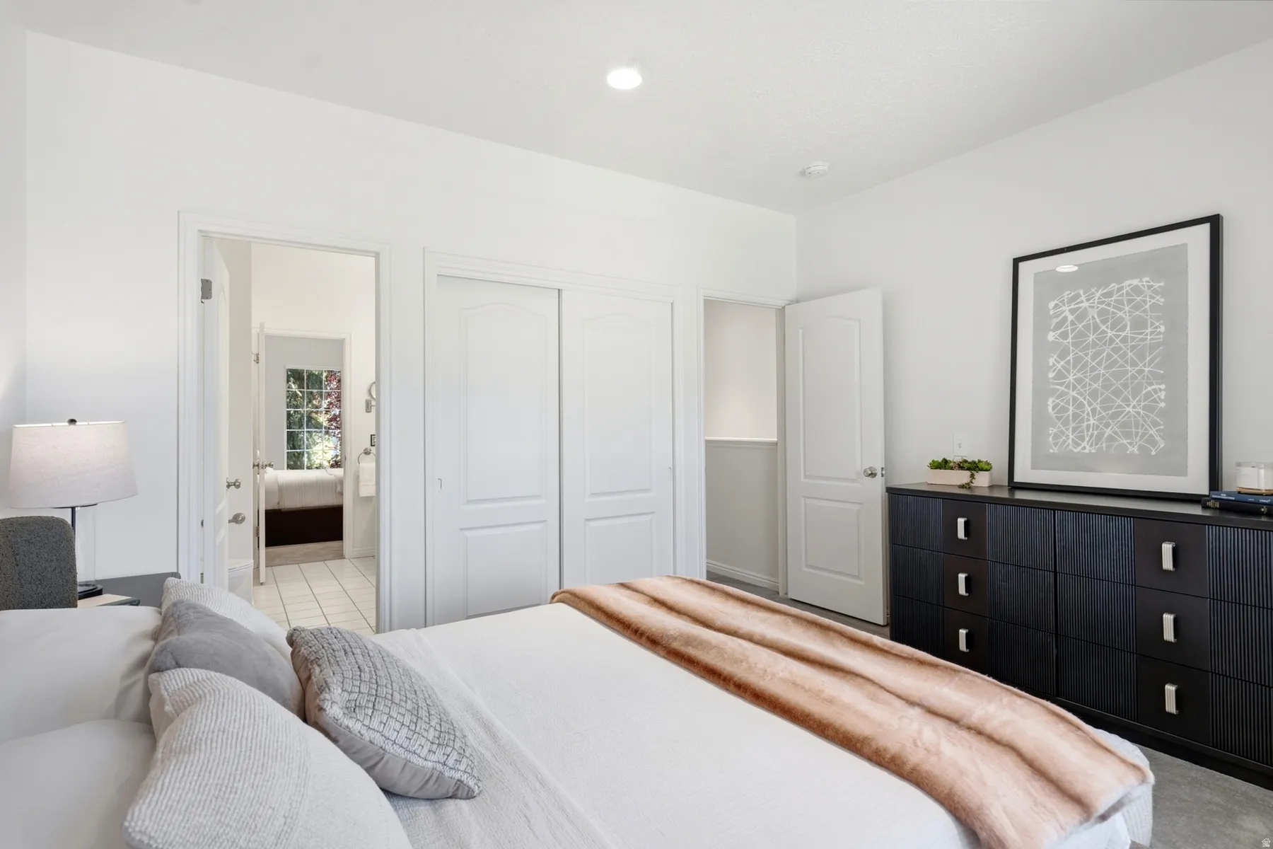 Recessed lighting illuminates the white walls and white trim throughout