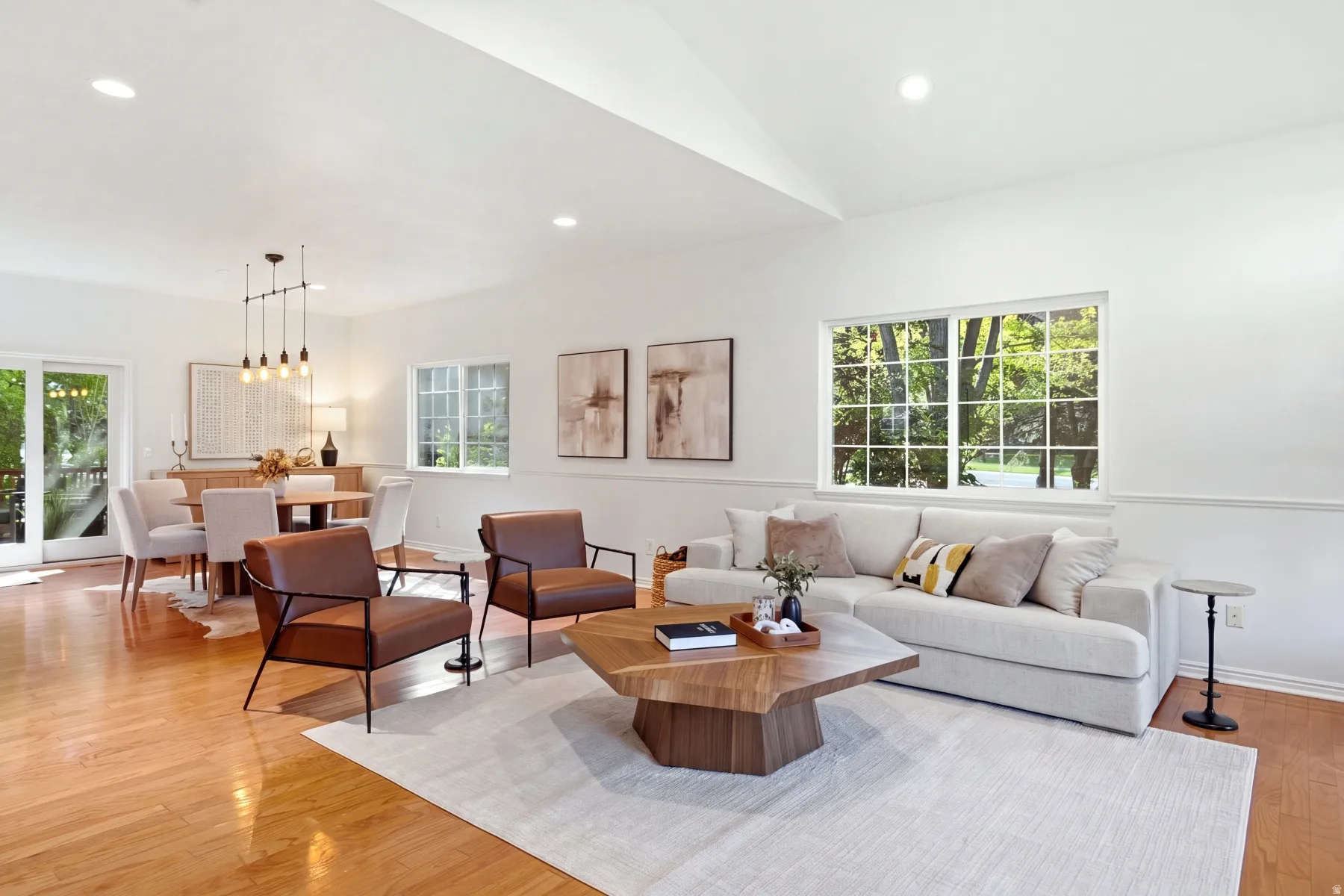 Open-concept living and dining areas featuring wood-finish flooring, recessed lighting, and a vaulted ceiling