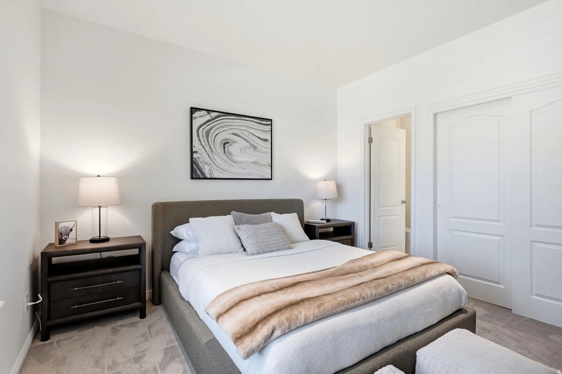 Neutral tone wall paint, carpet flooring, dual closet doors with arched paneling, and an interior door