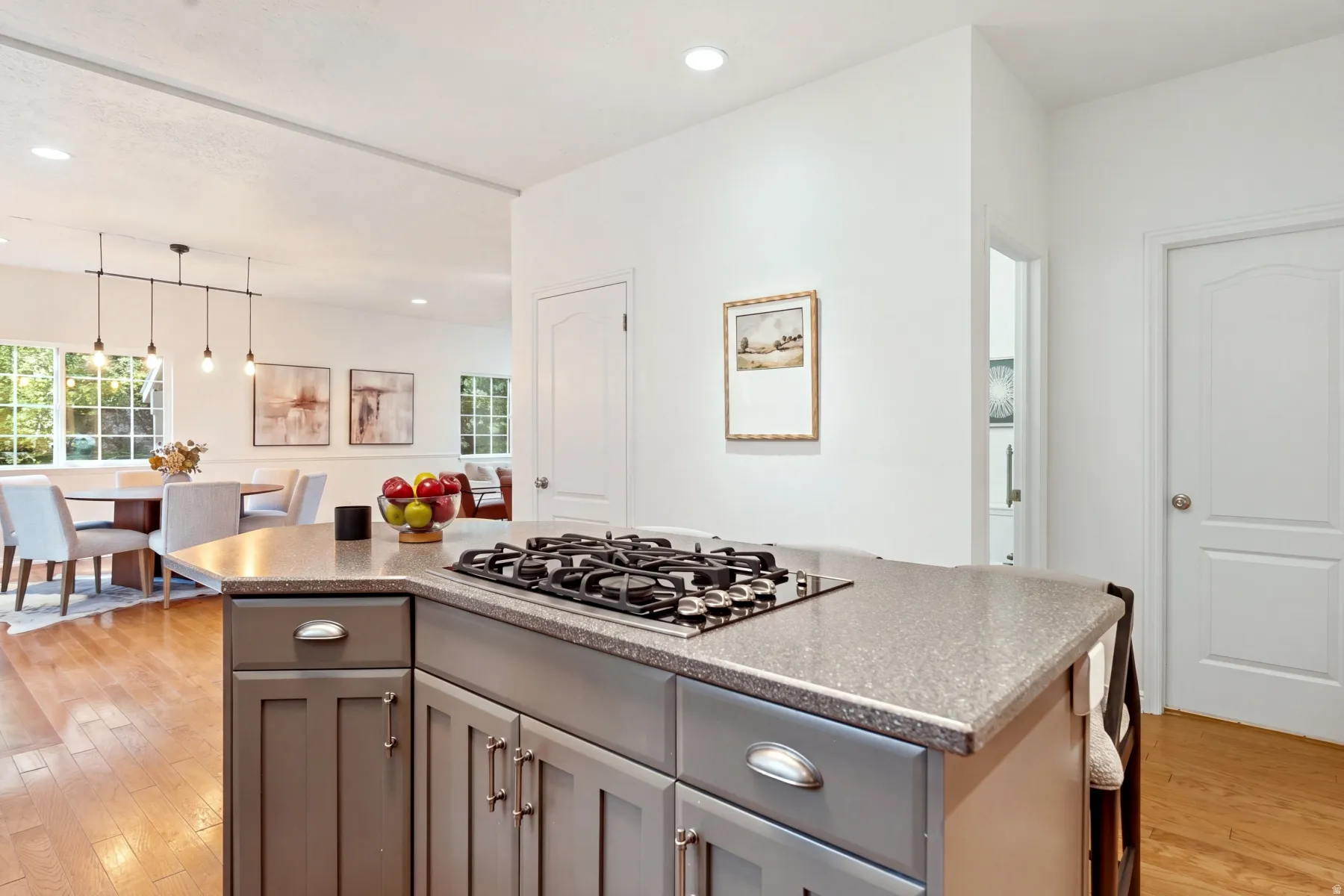Kitchen island with an integrated cooktop, gray cabinetry, and a light-toned countertop