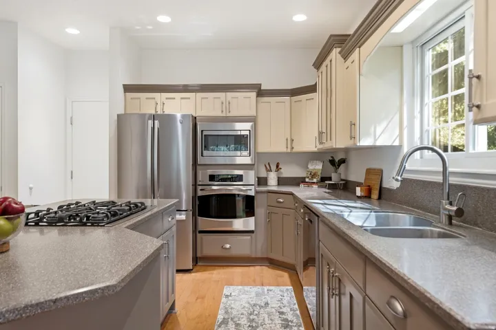 Kitchen featuring stainless steel appliances, dual-tone cabinetry, a built-in oven, a gas cooktop, and an undermount double-basin sink