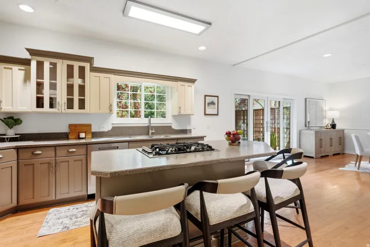 Kitchen featuring a central island with a gas cooktop, light-toned cabinetry, and a window above the sink