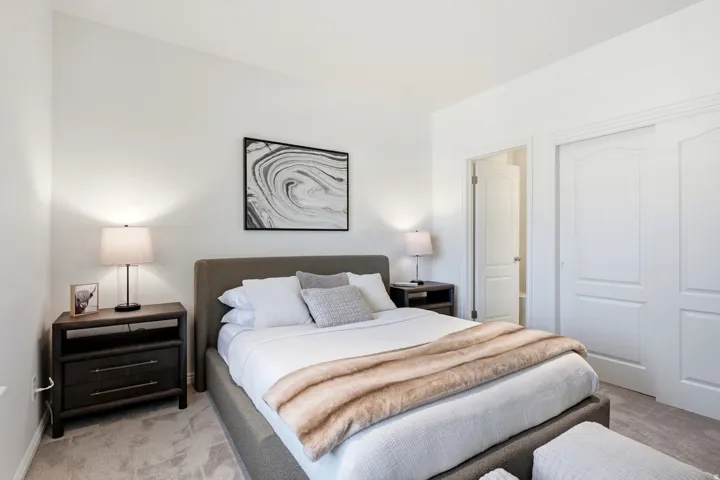 Neutral tone wall paint, carpet flooring, dual closet doors with arched paneling, and an interior door
