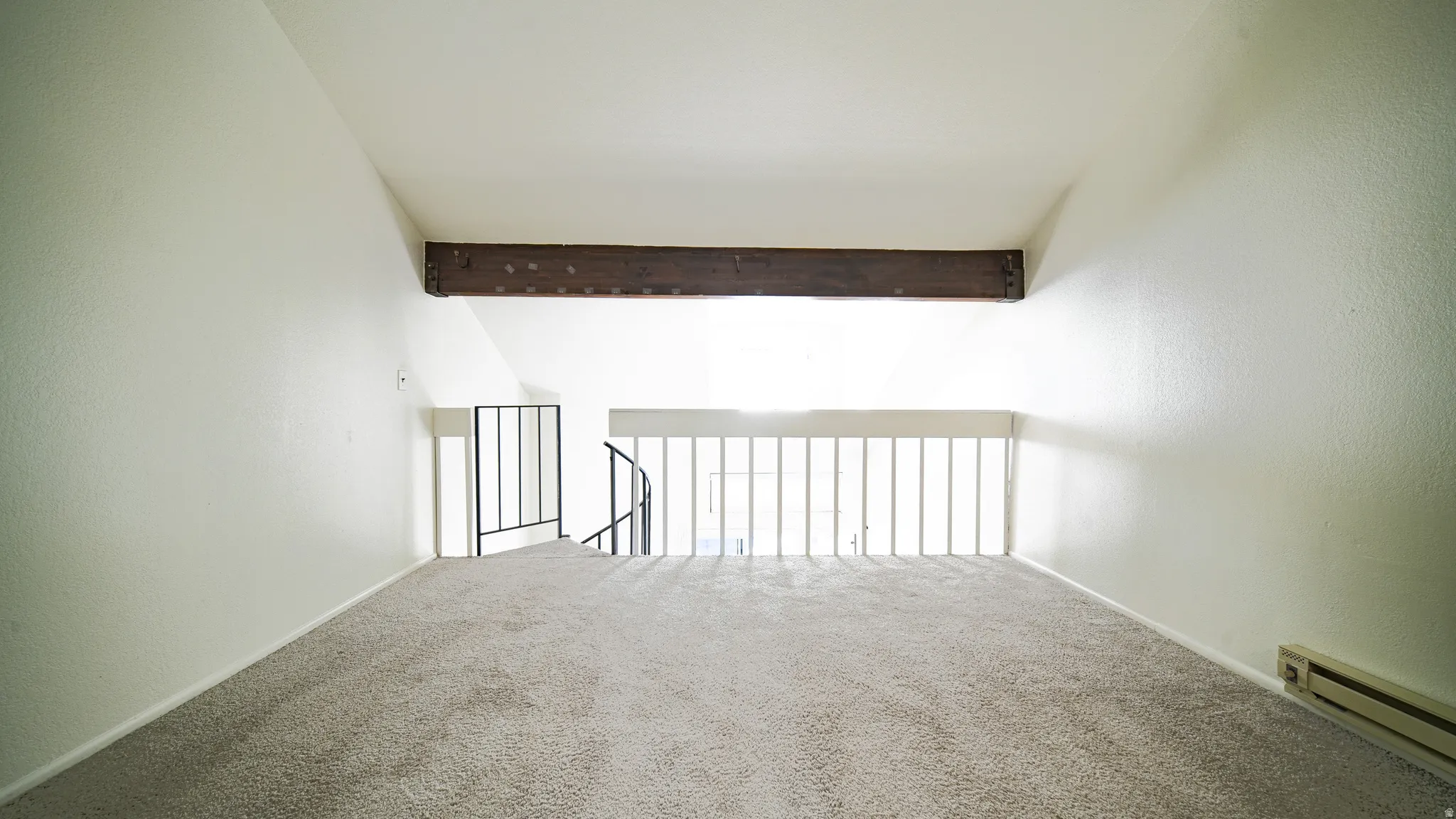 Loft space with vaulted ceiling, exposed wood beam, carpeted flooring, and metal railings