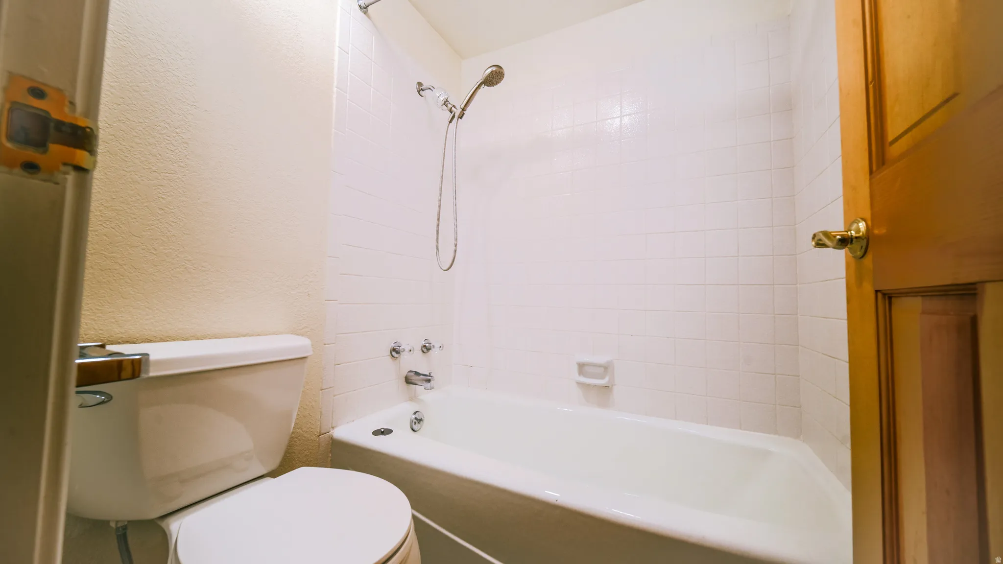 White tile shower surround with a fixed showerhead and separate bathtub faucet