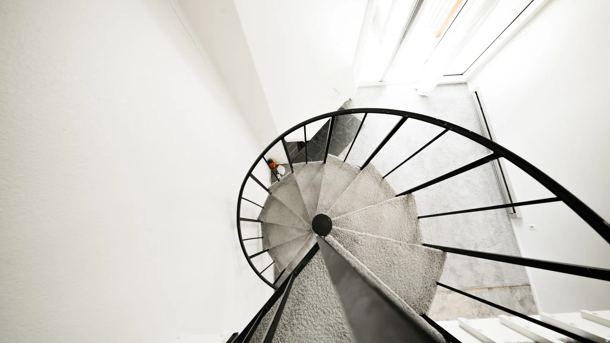 Spiral staircase with metal railing and carpeted treads