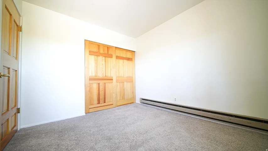 Carpeted flooring, natural wood doors, and baseboard heating
