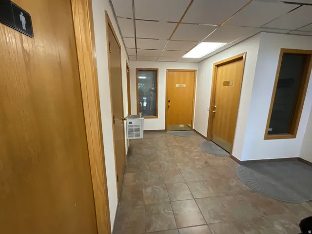 Tile flooring, drop ceiling with integrated lighting, wood-finish doors, and a built-in water cooler