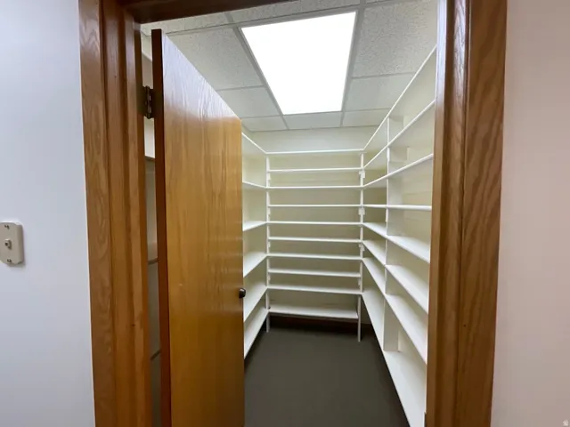 Wood-finish door frame opening to a room with extensive built-in white shelving