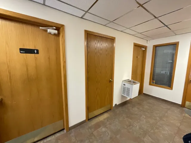Hardwood doors with door closers, tiled flooring, and a wall-mounted water cooler