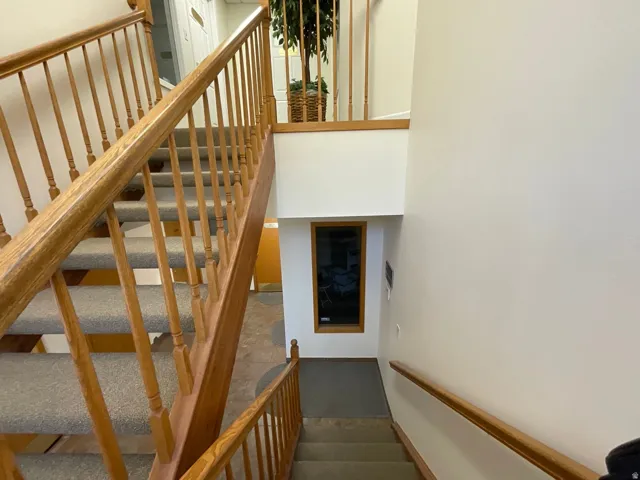 Dual-level staircase with wood railings and carpeted treads