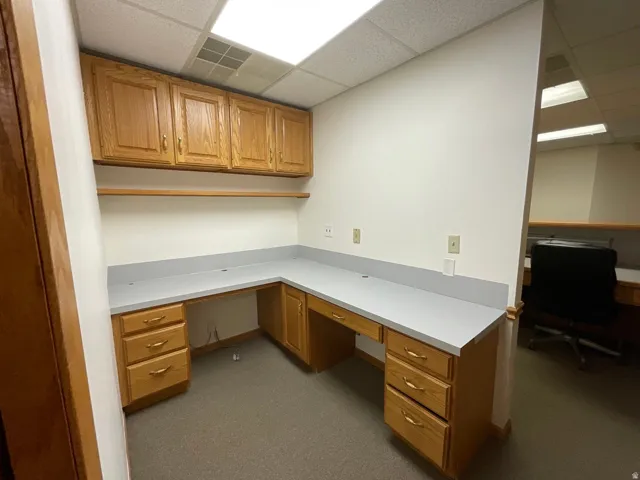 Built-in desk with wood cabinetry, light-toned countertops, and overhead storage