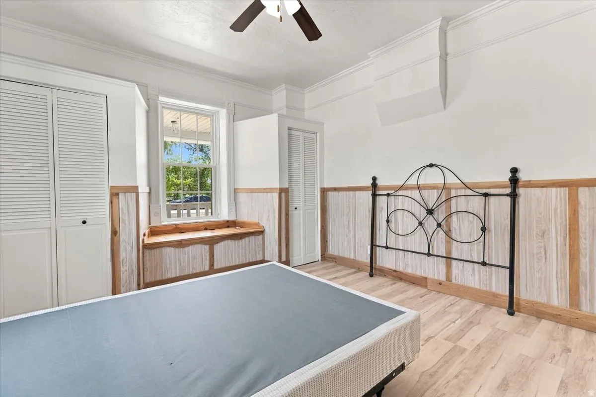 Wood-finish flooring with wainscoting details, louvered closet doors, and a built-in window seat
