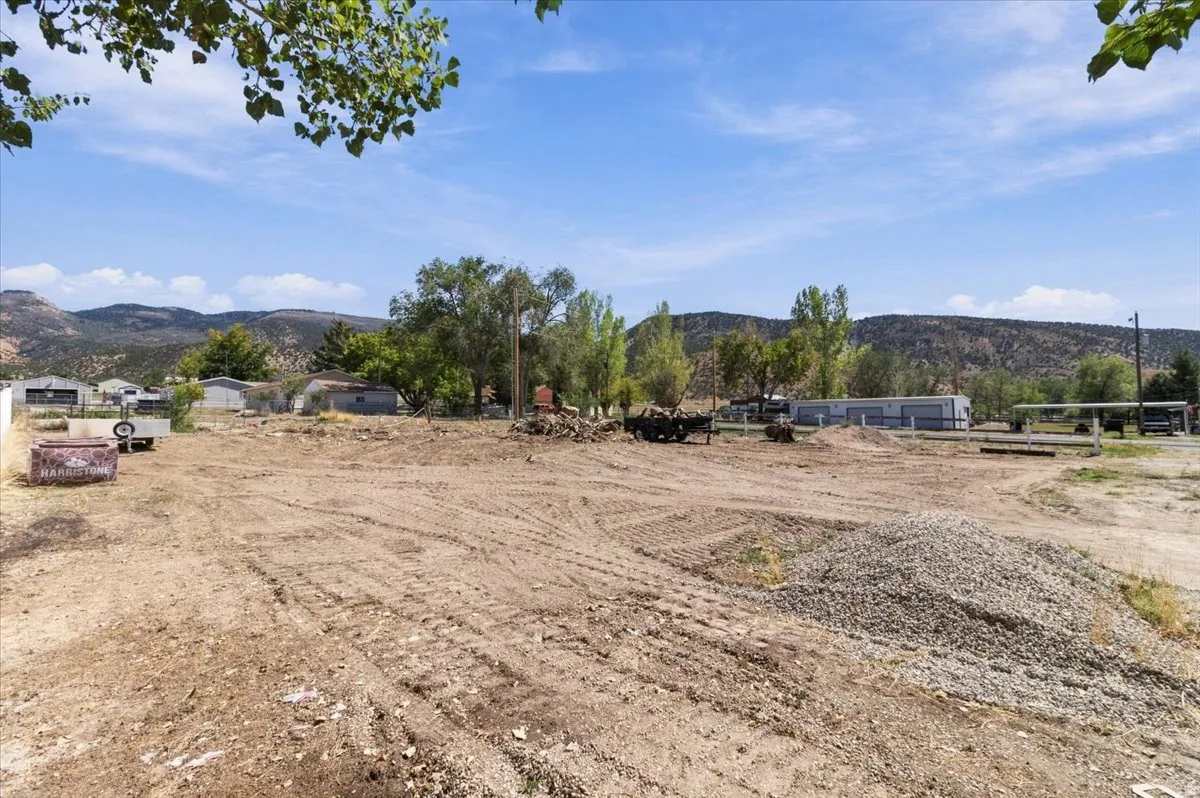 Expansive cleared lot with a prominent gravel pile and distant mountain backdrop
