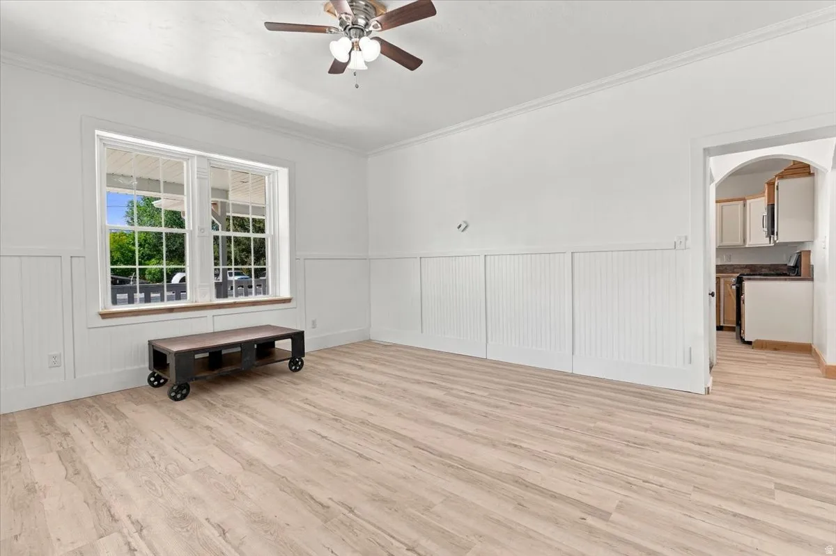 Light wood-finish flooring with white wainscoting and crown molding