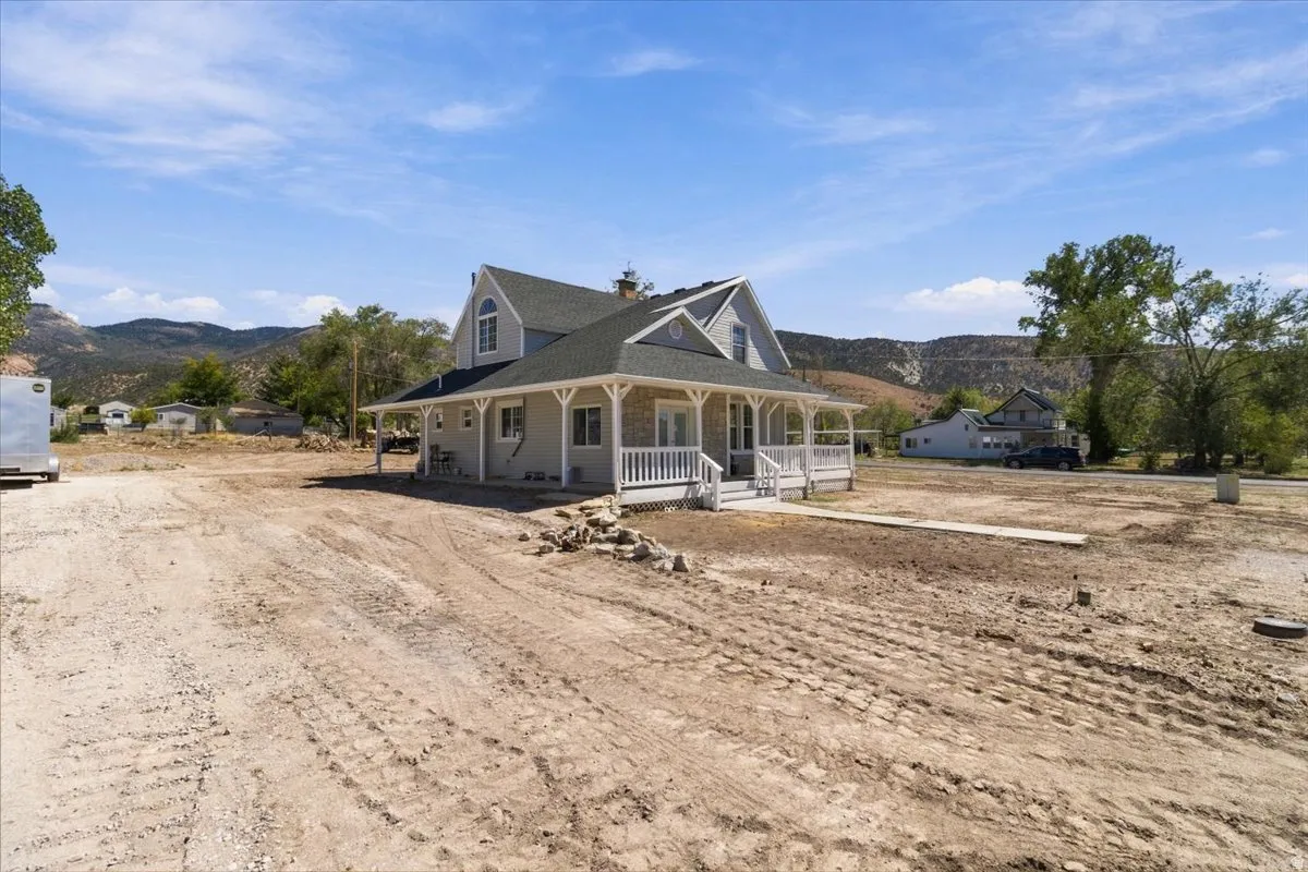 Exterior featuring a dormer window, covered porch, white porch railing, and stone façade accents