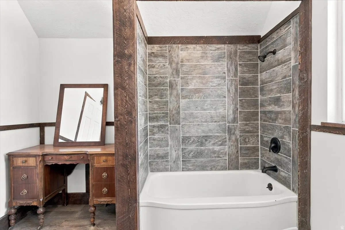 Alcove bathtub with wood-finish tile surround and matte black fixtures