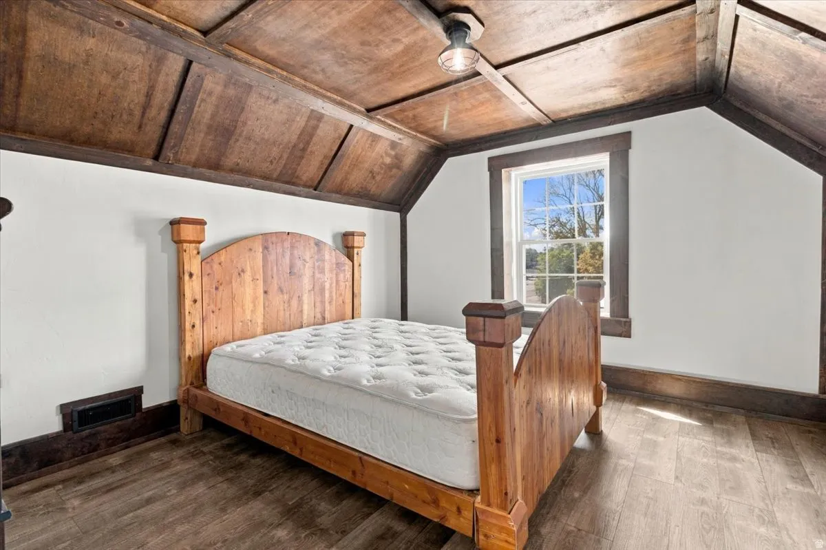 Vaulted wood-paneled ceiling with exposed beams, wood-finish flooring, and a window with wood trim