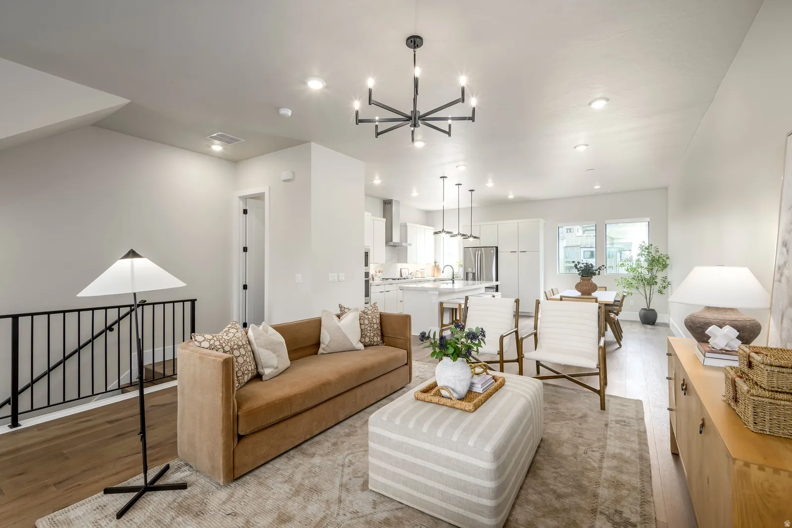 Open-concept living area featuring wood-finish flooring, recessed lighting, and a contemporary chandelier