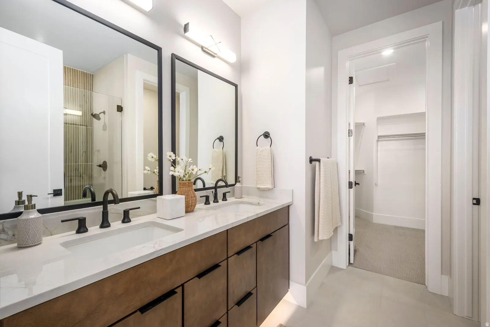 Dual vanity with integrated sinks, matte black fixtures, and a spacious walk-in closet