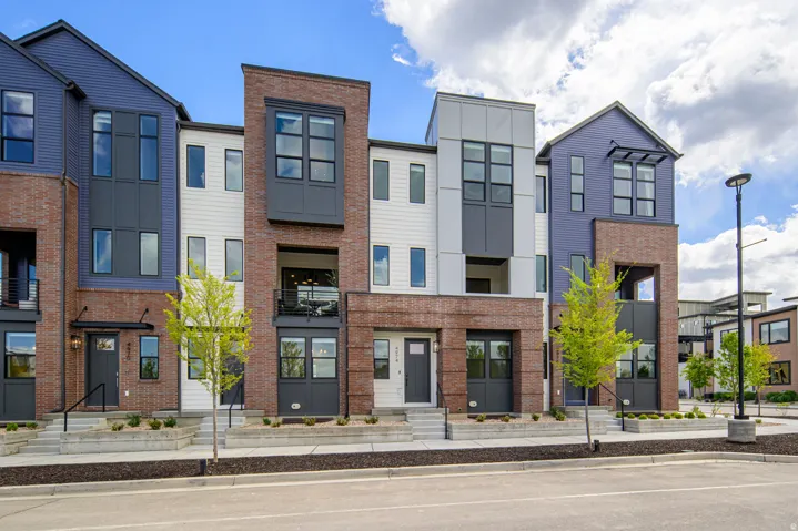 Modern multi-story facade featuring brick, dark siding, and white paneling