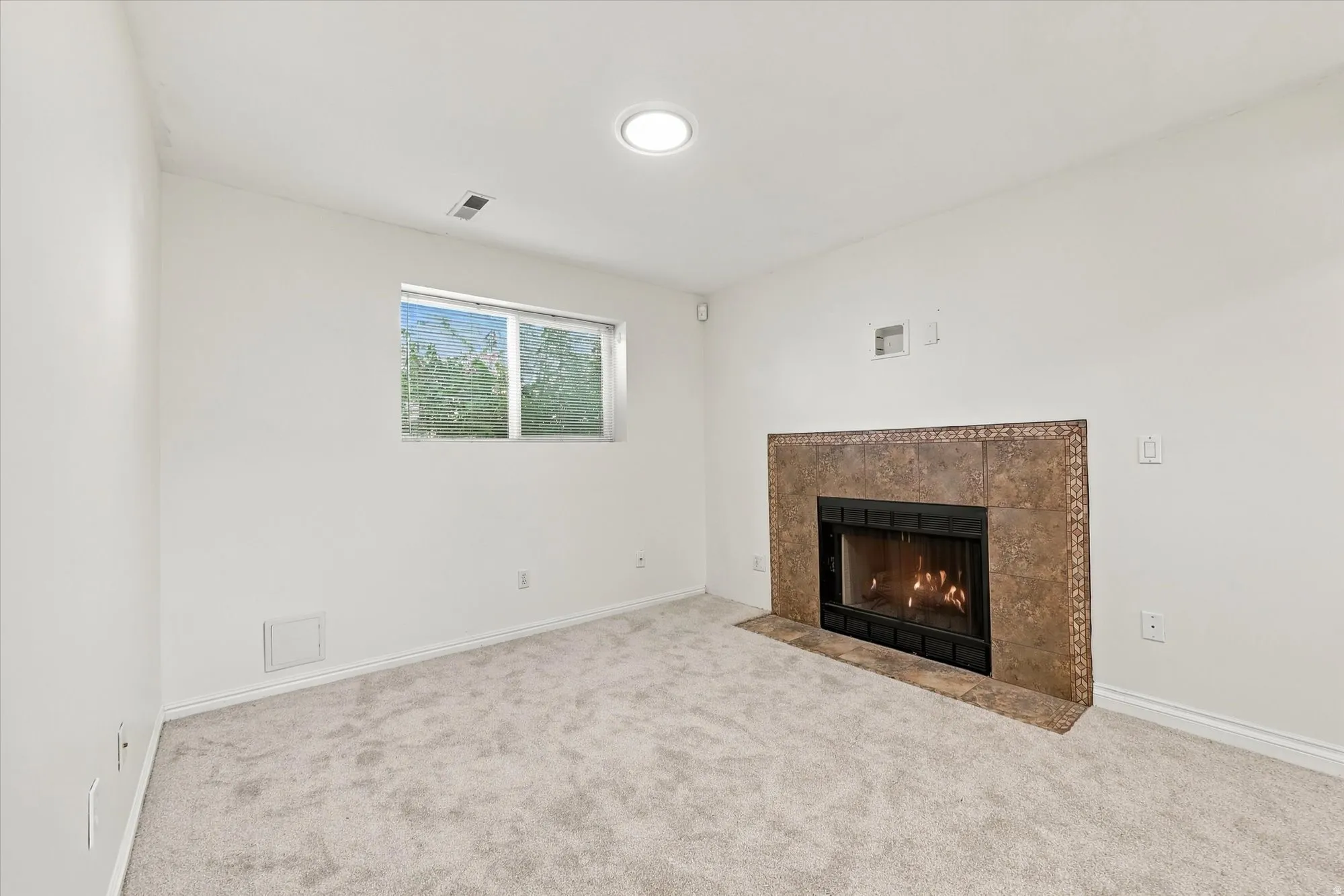 Recessed lighting, tile-surround fireplace, light-colored carpeting, single window, and neutral wall finishes
