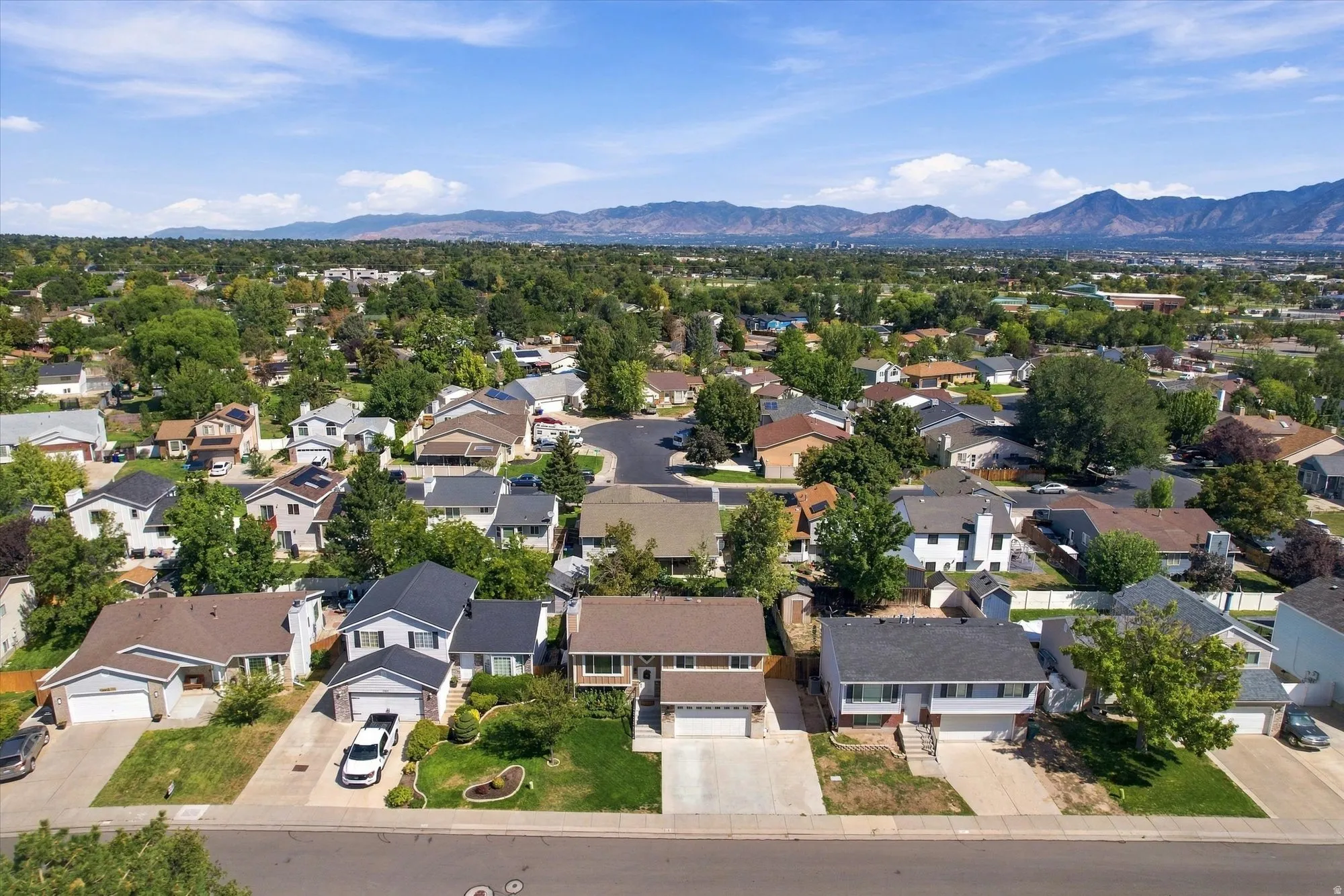Residential neighborhood featuring mature trees and distant mountain ranges