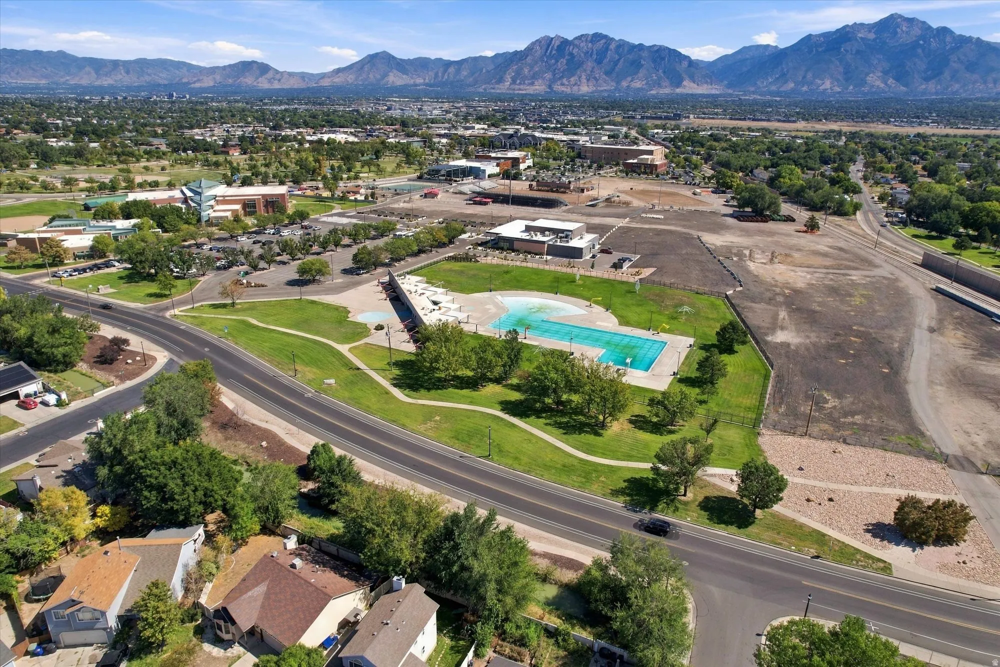 Expansive community featuring a large outdoor swimming pool, surrounding green spaces, and mountain backdrop