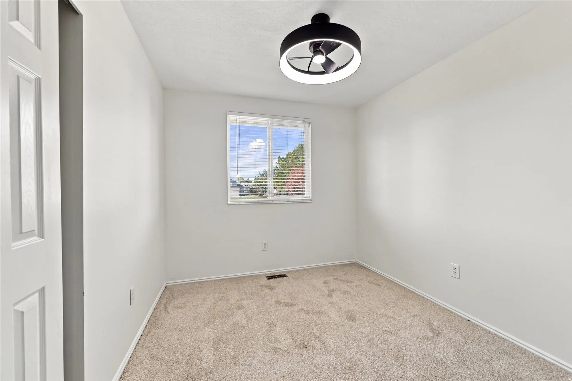 Recessed window with blinds, overhead lighting, neutral carpeting, and white walls