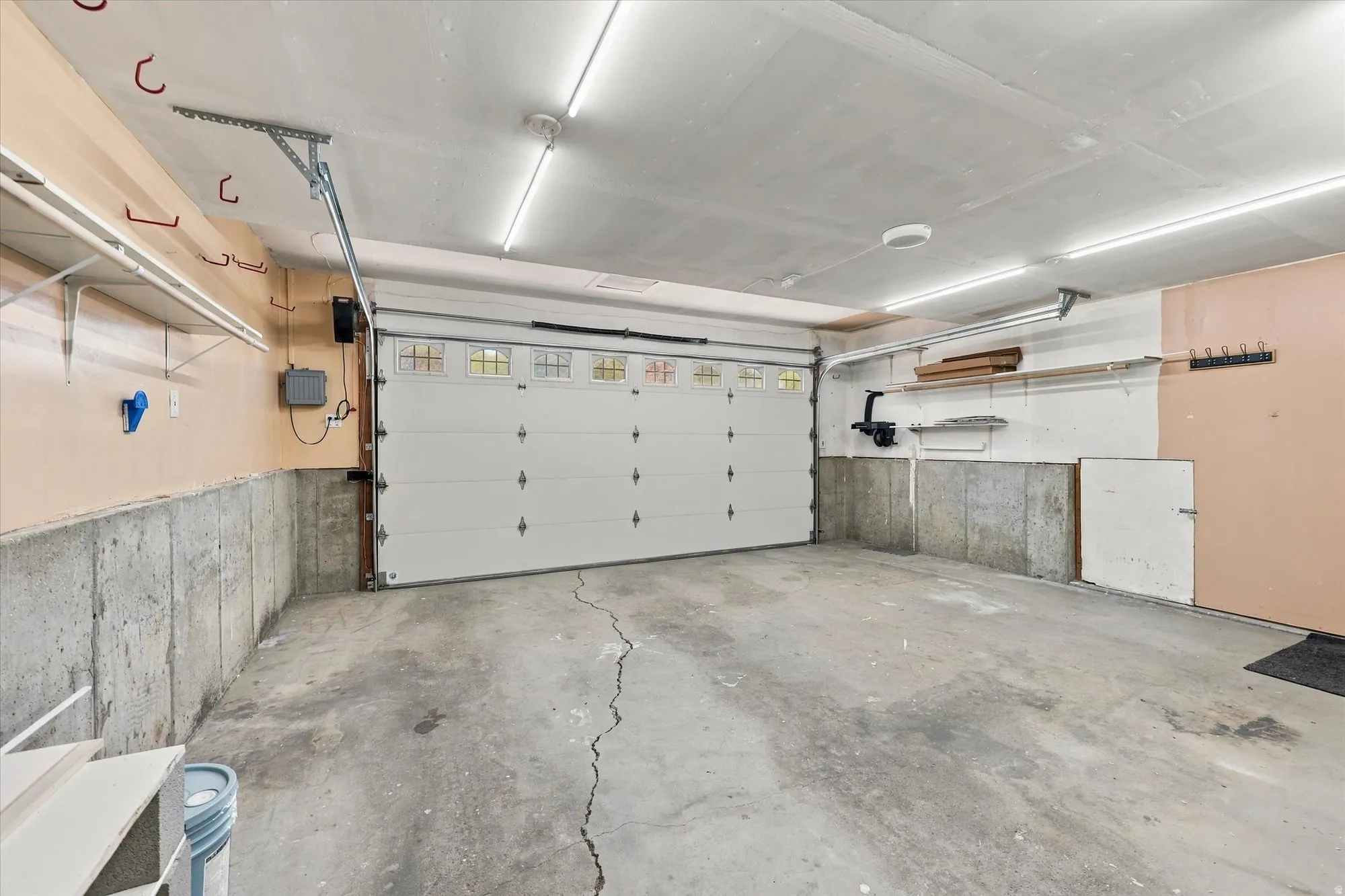 Attached two-car garage with overhead lighting, concrete flooring, and a sectional garage door with upper-level window panes