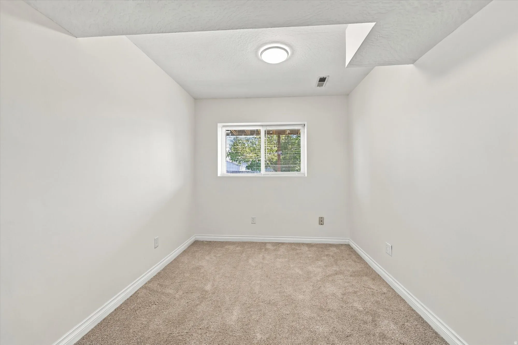 Recessed ceiling light, neutral wall paint, carpeted flooring, window, and white trim
