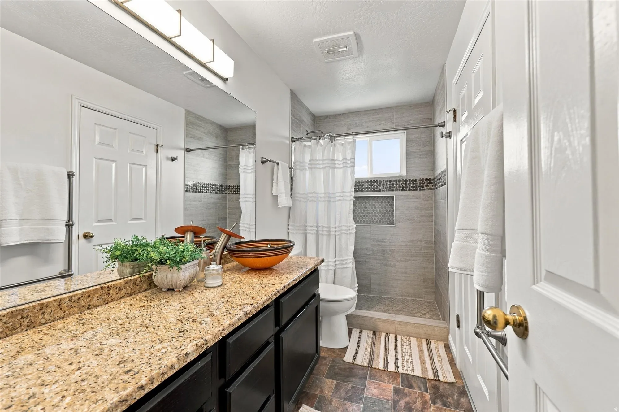 Vanity with granite-style countertop, dark wood-finish cabinetry, and a large mirror