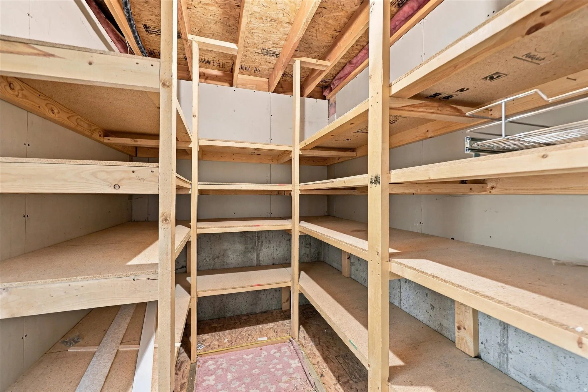 Expansive storage area featuring multiple tiers of wood shelving and exposed ceiling joists