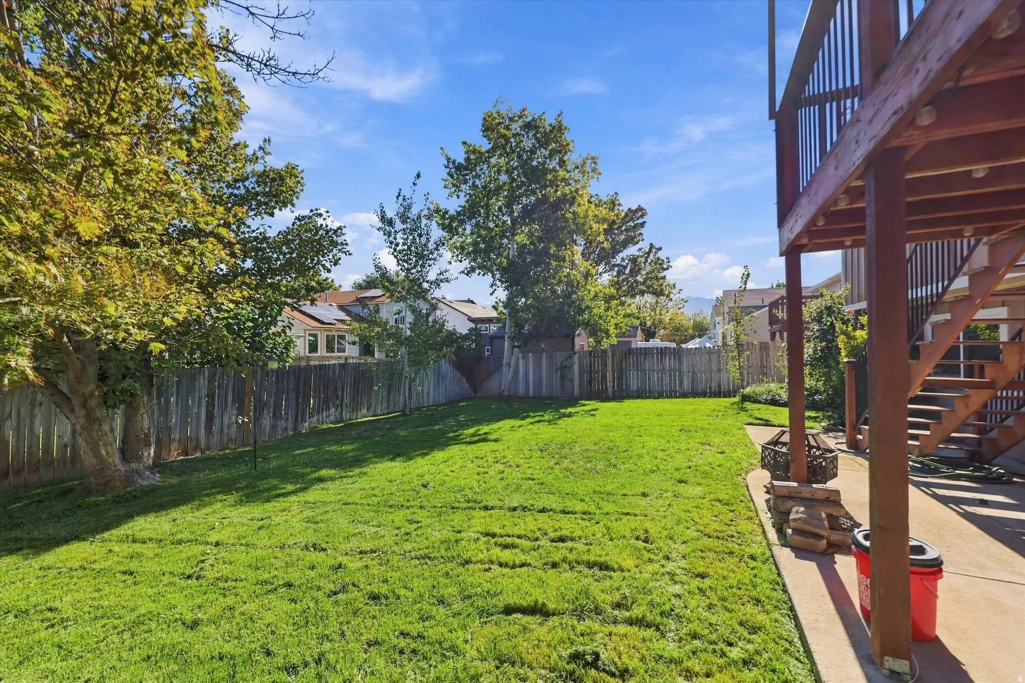 Expansive grassy yard with mature trees and wood fencing