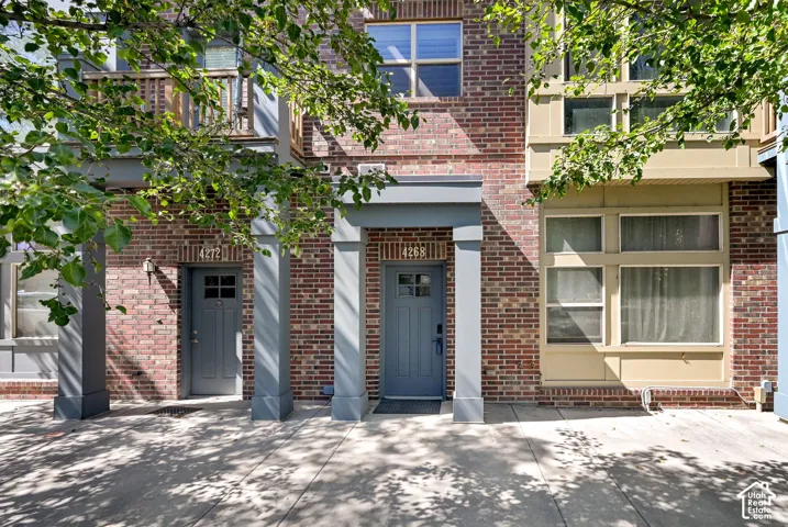 Mid-row Townhome with brick exterior and a tree lined street
