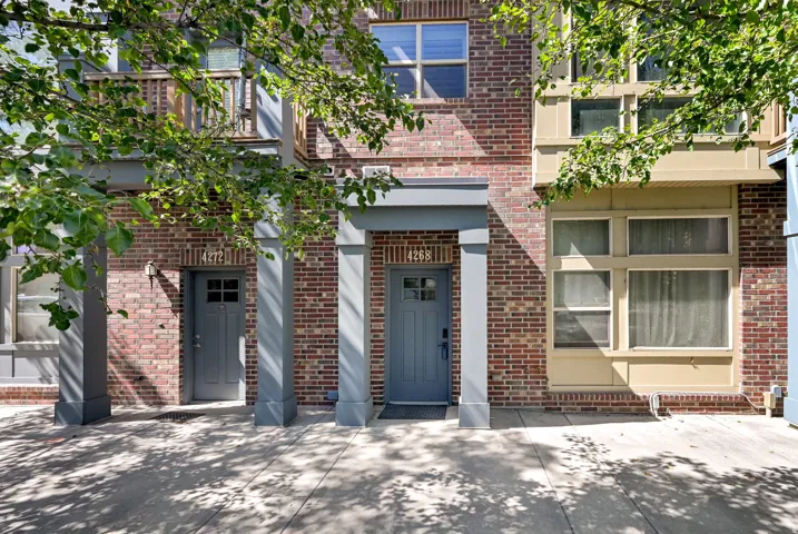 Mid-row Townhome with brick exterior and a tree lined street