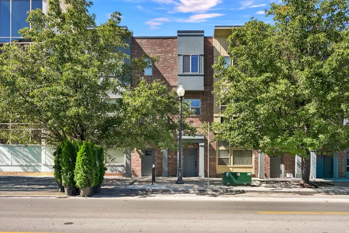 Mid-row Townhome with brick exterior and a tree lined street