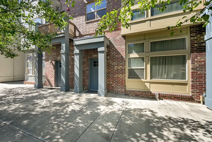 Mid-row Townhome with brick exterior and a tree lined street
